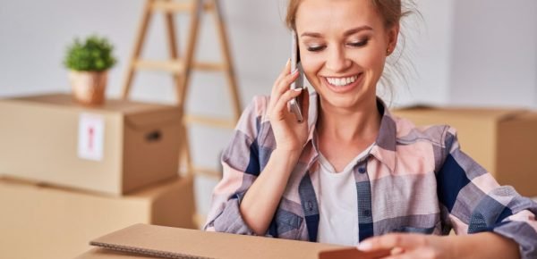 smiling-woman-using-phone-while-moving-house-min